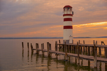 Wooden pier bathed in warm bronze light, with soft ripples on the water and a moody evening sky...