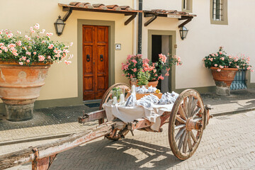 Old wooden cart as a party decor with wedding favors and gifts for guests. Rustic Italian villa...