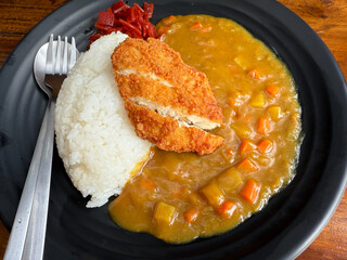 Black and white cat lying on the concrete floor, with bright pink nose and golden eyes, looking calmly