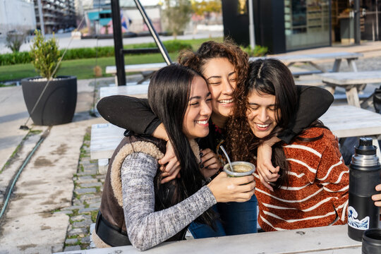 Latin american women sharing mate outdoors and embracing friendship - Powered by Adobe