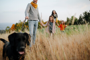 Family took dog on walk in autumn nature.