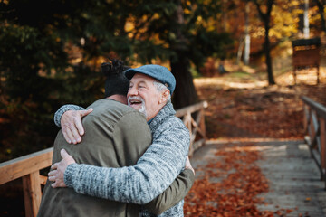 Fototapeta premium Grandad and grandson hugging in the middle of autumn park.