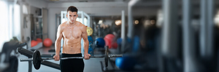 Focused Shirtless Man Lifting Weight in Gym Wide Banner
