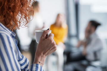Close up of woman holding coffee in office kitchen.