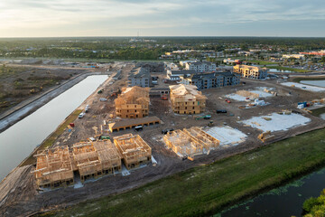 Unfinished frames of apartment condos with wooden roofs under construction. Development of...