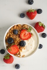 Tasty yogurt with granola and berries on white marble table, flat lay