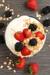 Tasty yogurt with granola and berries in bowl on wooden table, flat lay