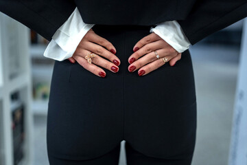 Woman in black suit with elegant rings and red nails