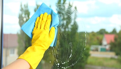 Hand in yellow glove cleaning a window