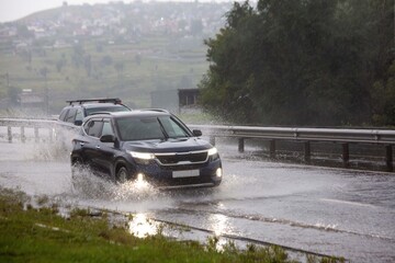 Car in splashes of water on the road. Precipitation, climate.