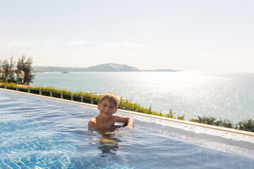 Child with mother in swimming pool, enjoying hppy family summer vacation on the beach and in resort