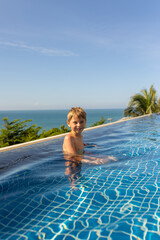 Child with mother in swimming pool, enjoying hppy family summer vacation on the beach and in resort