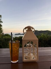 Iced Tea and Lantern on Wooden Table with Scenic Ocean View