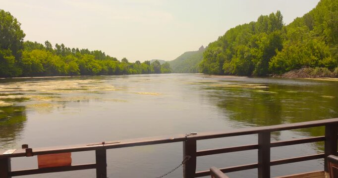 A peaceful view from the deck of a traditional gabare boat, as it cruises serenely down the beautiful and historic Dordogne River in France.