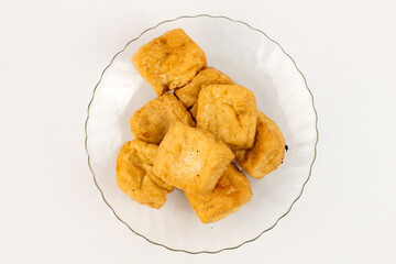 Crispy fried tofu cubes served on elegant glass plate, ready for delicious vegan meals and healthy...