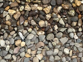 Natural background of multicolored smooth river stones and pebbles in earthy tones, ideal for...