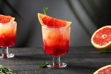 Cocktail or mocktail with grapefruit tonic and red grenadine syrup in a stemmed glass garnished...