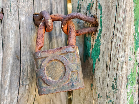 Close-up of an old, rusty padlock on a weathered wooden gate. Vintage concept of security, privacy, and forgotten secrets.