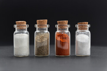 Spice mix:  white salt, ground black pepper, paprika and sugar in front of a black background.