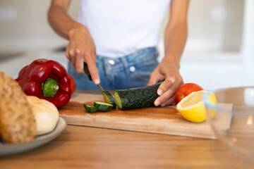 Young woman preparing fresh vegetables and fruits in a modern kitchen. Concept of clean eating, wellness, natural lifestyle, and healthy food preparation.