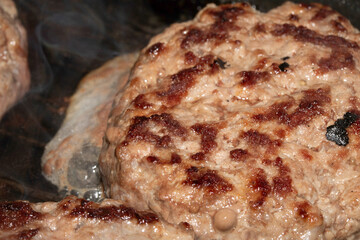 Close up of fresh beef burgers frying an a pan