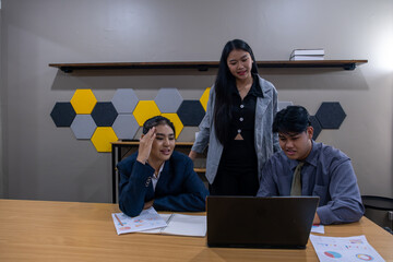 Team collaborates in modern office setting analyzing data on laptop during afternoon work session