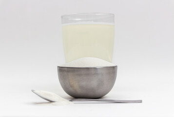 Spilled, dry collagen powder in metal container and spoon next to liquid, dissolved collagen as...