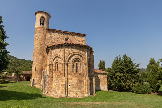 San Martin de Elines, Spain. Romanesque apse and cylindrical bell tower of the collegiate church, built in the 12th century, under clear summer blue sky