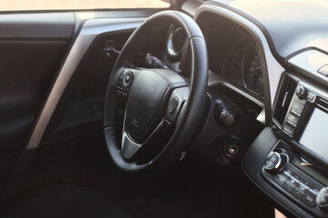 Closeup of a modern car steering wheel with control buttons for technology and convenience