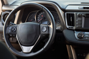 Fototapeta premium Closeup of a modern car steering wheel with control buttons for technology and convenience