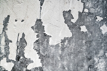 Closeup view of heavily textured white painted concrete wall. The surface is old and worn with...