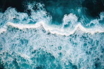 Fototapeta premium Aerial view of ocean waves crashing and foaming with vibrant turquoise and white colors, showcasing nature's dynamic water movement.