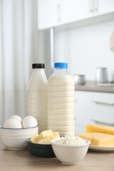 Different dairy products and eggs on wooden table in kitchen