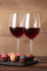 Delicious truffle bonbons and wine on wooden table