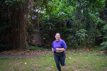 Indonesian southeast asian overweight woman in a sporty outfit practices running exercise in a...