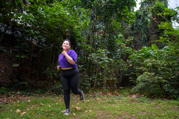 Indonesian southeast asian overweight woman in a sporty outfit practices running exercise in a...