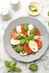Tasty salad Caprese with mozzarella, tomatoes, basil and spices on white marble table, flat lay