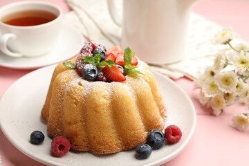 Delicious bundt cake with powdered sugar, berries and mint on pink wooden table, closeup