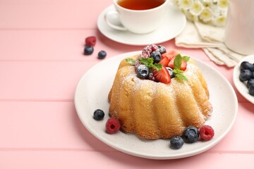 Delicious bundt cake with powdered sugar, berries and mint on pink wooden table, closeup