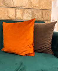 A soft velvet sofa with two pillows, orange and brown, creates cozy contrast in the room. Comfort,...
