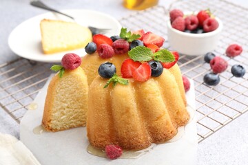 Tasty Bundt cake with berries, honey and mint on light grey table, closeup