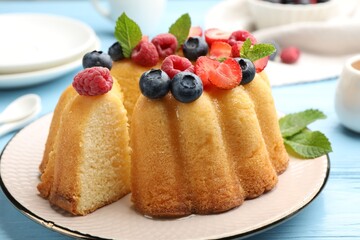 Tasty Bundt cake with berries and mint on light blue wooden table, closeup