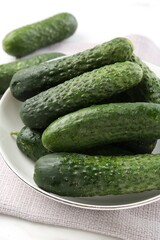 Fresh cucumbers in bowl on white table, closeup