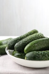 Fresh cucumbers in bowl on white table against grey background, closeup