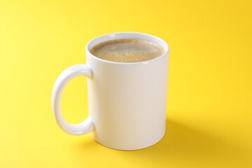 Aromatic coffee in cup on yellow background, closeup. Mockup for design
