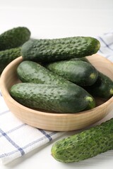 Fresh cucumbers in bowl on white wooden table, closeup