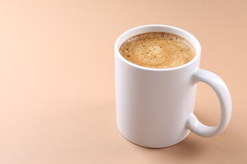 Fototapeta premium Aromatic coffee in cup on beige background, closeup. Space for text