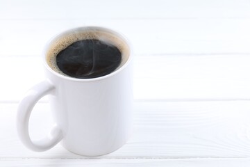 Aromatic coffee in cup on white wooden table, closeup. Space for text