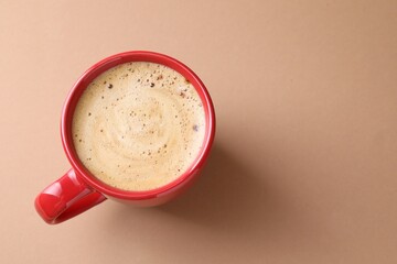 Aromatic coffee in cup on beige background, top view. Space for text