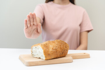 Gluten allergy, asian young woman hand push out, refusing to eat white bread loaf on board in...